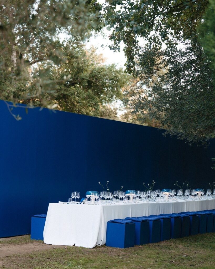 Long white dining table with cobalt blue seating against a matching blue wall.