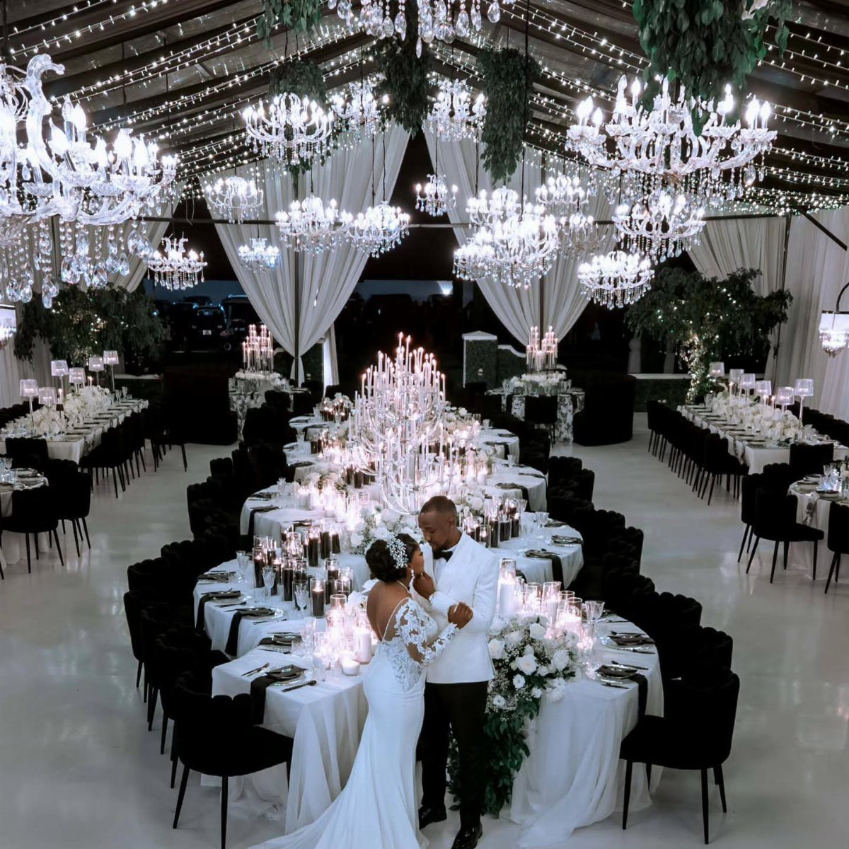 Bride and groom embracing in a luxury wedding venue with crystal chandeliers.