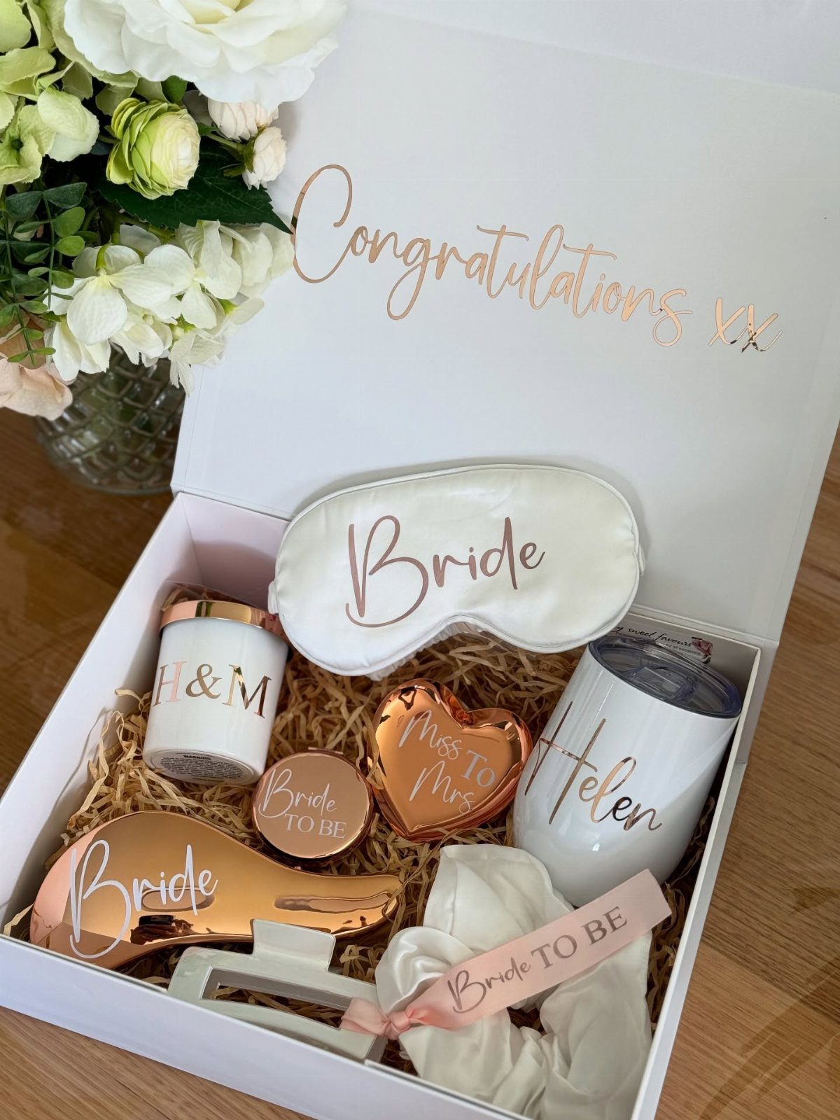 White gift box containing bridal themed accessories like a sleep mask and tumbler.