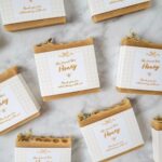 Honey-colored soap bars wrapped in white paper bands with gold bee labels.