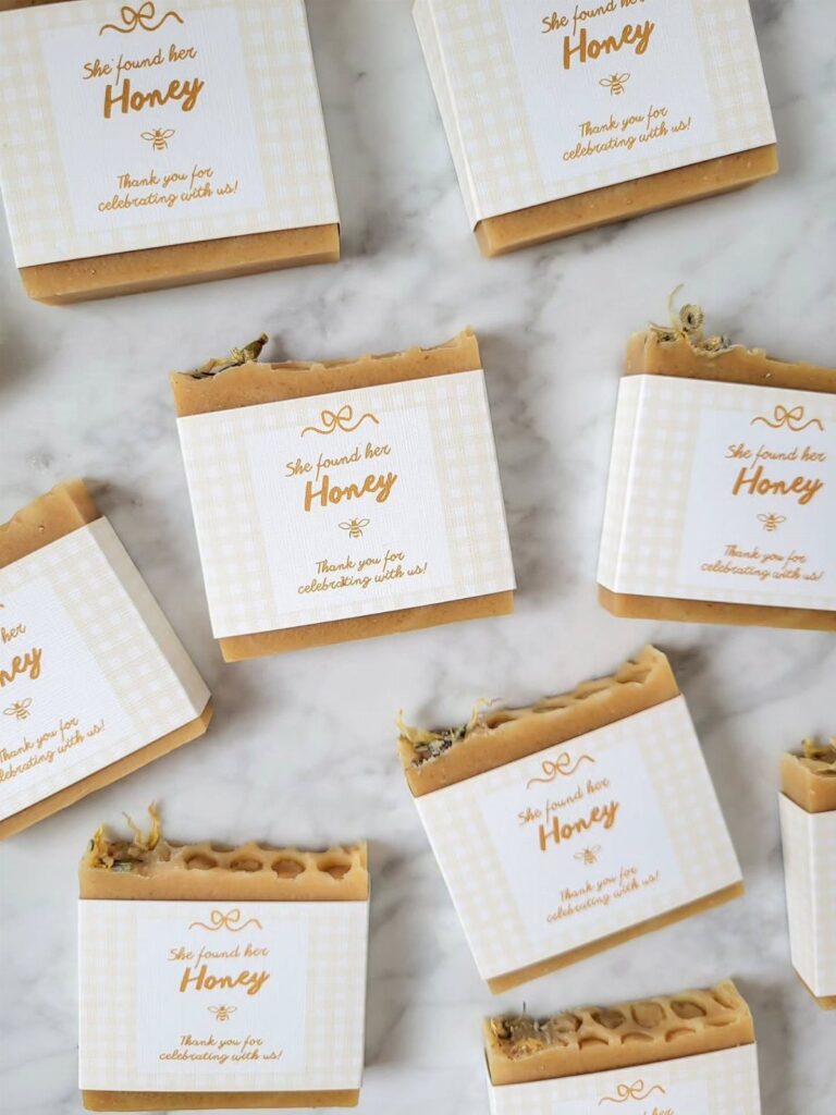Honey-colored soap bars wrapped in white paper bands with gold bee labels.