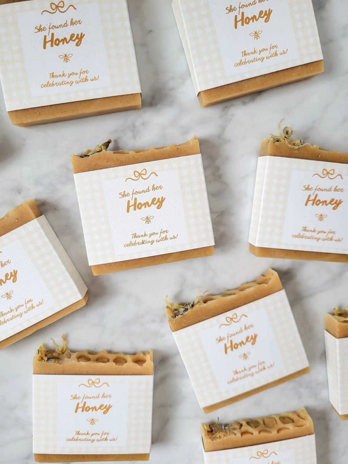 Honey-colored soap bars wrapped in white paper bands with gold bee labels.