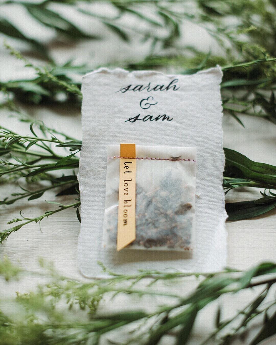 Seed packet with yellow ribbon on a personalized card surrounded by green leaves