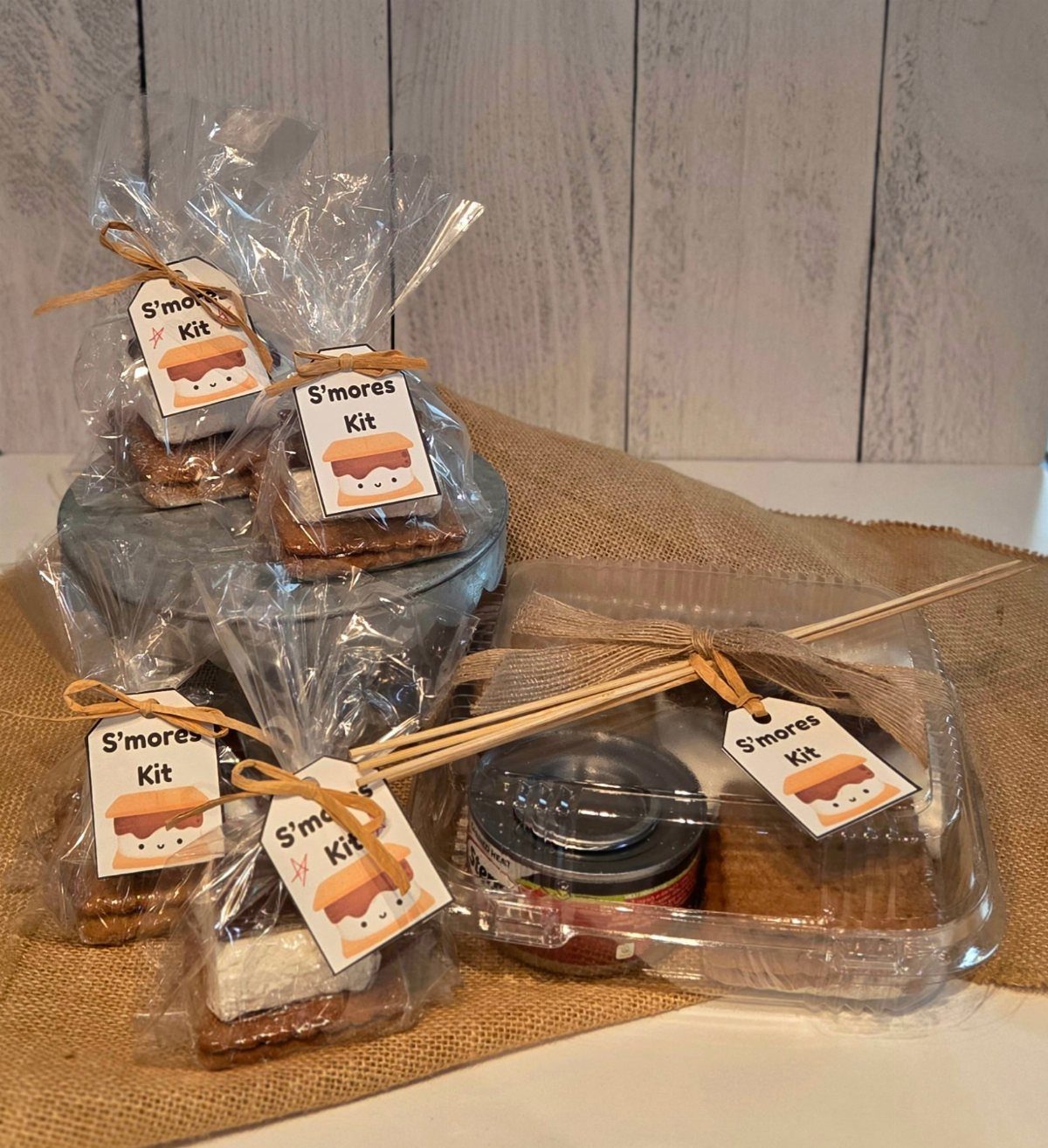 S'mores kits in clear packaging with custom tags tied with twine on burlap.