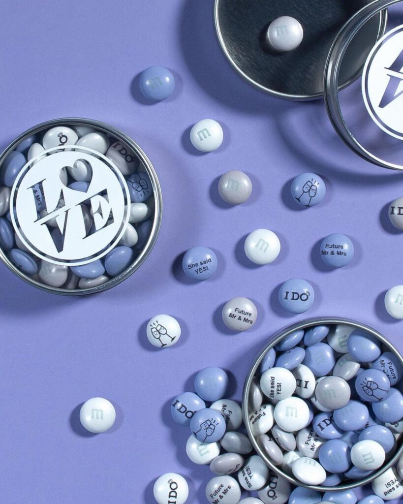 Blue and white M&M's with wedding text and clip art in metal tins.