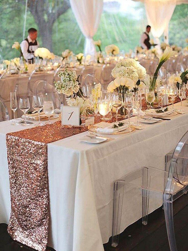Wedding table with white linens, rose gold sequin runner, and white floral centerpieces.
