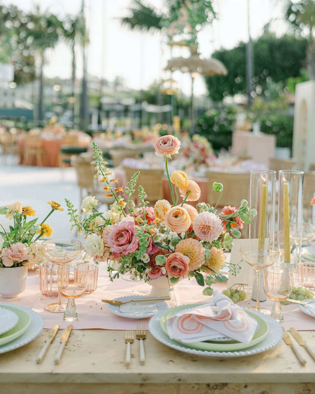 Peach and sage wedding table decor with floral centerpiece and gold cutlery.