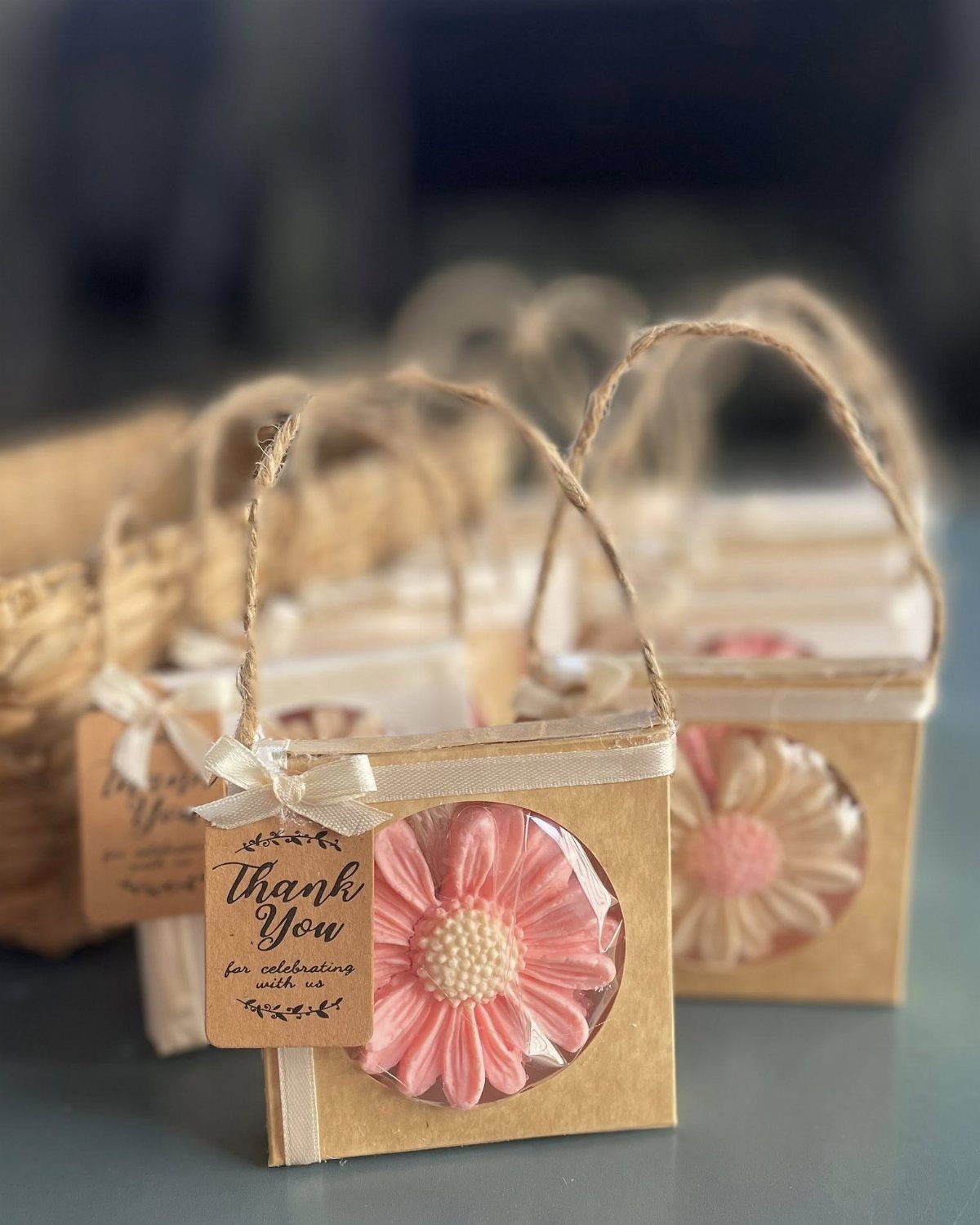 Pink flower-shaped soap bars in small brown gift boxes with thank you tags.