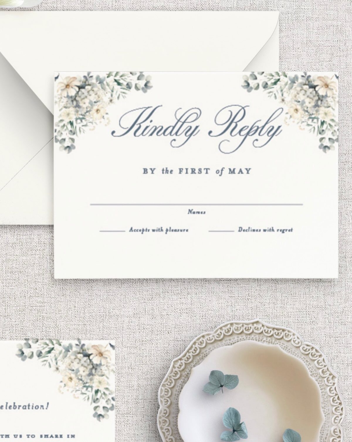 Wedding RSVP card with blue and green floral accents on beige fabric background