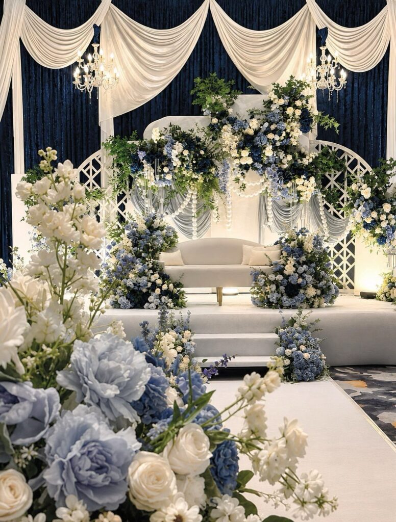 Wedding stage with navy blue curtains, white drapes, and blue and white flowers.