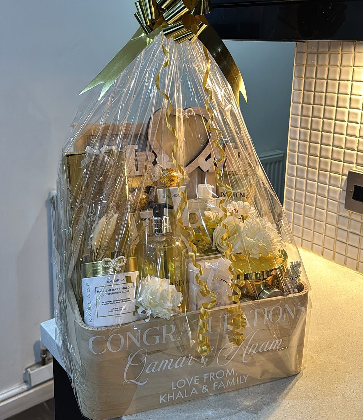 Wedding gift hamper wrapped in cellophane with gold bow and congratulatory text.