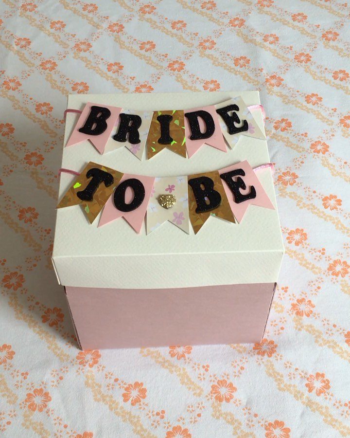 Pink and white gift box with Bride to Be banners on floral fabric